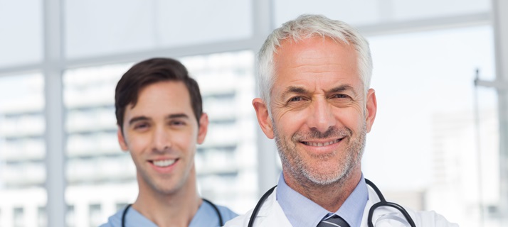 50s, Mature Adult, Man, Male, Caucasian, 20s, Young Adult, Indoors, Looking At Camera, Doctor, Practitioner, Profession, Professional, Specialist, Lab Coat, Stethoscope, Confident, Nurse, Scrubs, Blue, Standing, Clinic, Healthcare, Hospital, Medical, Staff, Attractive, Handsome, Grey Hair, Portrait, Team, Smiling, Happy, Cheerful, Friendly